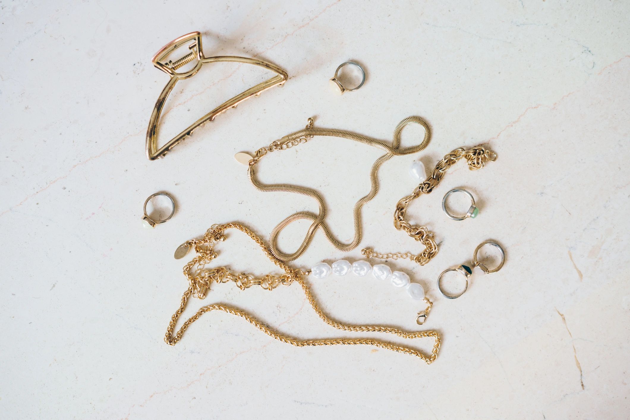 Gold jewelry and accessories arranged on a marble surface
